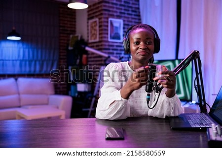 POV of woman influencer creating podcast content in studio, recording with camera and modern sound equipment. Female vlogger filming video and talking to audience for internet channel.