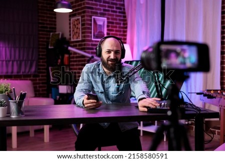 Male blogger filming video with podcast equipment in studio, recording online vlog and hosting talk show at station. Content creator using live broadcast on entertainment channel.