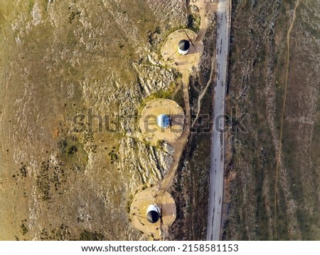 Aerial view of white cylindrical towers and pointed roofs of old Spanish windmills in the background with the urban landscape of Consuegra