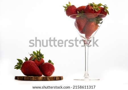 strawberries on a wooden board and a glass cup white background and copy space
