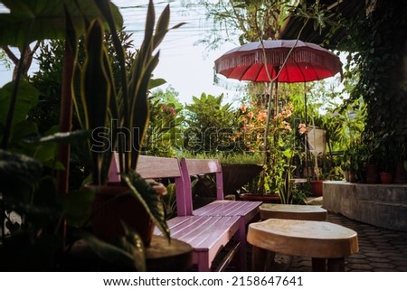 Sun umbrella and tables at cafe in tropical paradise. Space for chilling and green thick at backyard patio. Restaurant in Bali Canggu.