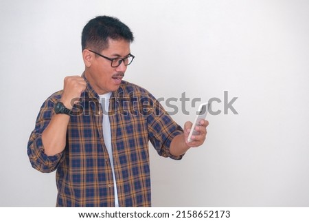 Asian guy with smartphone at hand to access mobile banking system from home