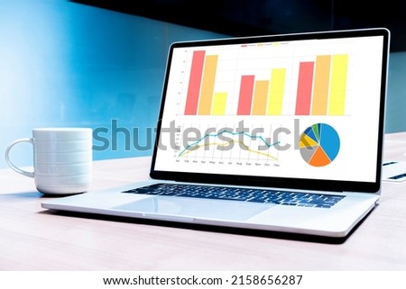 Coffee cup and laptop on table with mockup chart presentation slide show on display