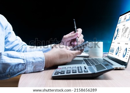 Businessman take note to notebook and laptop with mockup chart presentation slide show on display