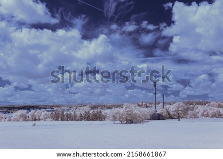 A scenic view of an agricultural field and trees under the clear sky - infrared photography