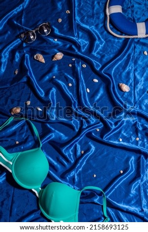 Marine still life: green swimsuit, glasses, seashells and a lifebuoy on a blue background
