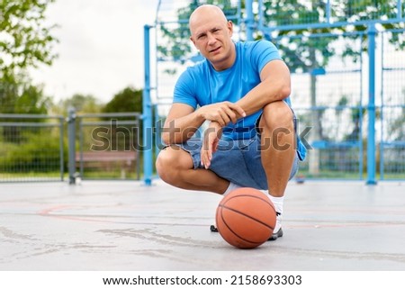 Handsome man carrying a basketball ball and looking at camera