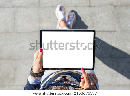 Woman using tablet computer with blank white screen, view from above