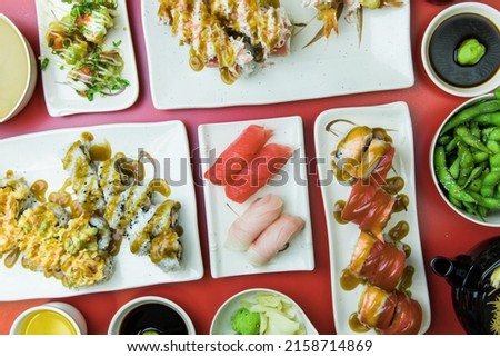 A closeup of sushi with various rolls, yellowtail nigiri, tuna nigiri, wasabi, edamame  Top view 