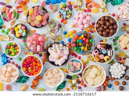 Milk chocolate and jelly gums candies on blue with liquorice allsorts and strawberry bonbons and large variety of sweets and candies. Top view Royalty-Free Stock Photo #2158716617