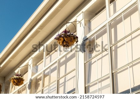 A low angle shot of two flowers pots hanging on the facade of a white building in bright sunlight in Murrells Inlet, Georgetown, SC, United States