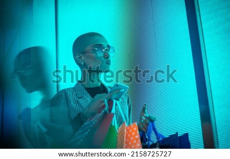 Image of a beautiful young woman posing against a led panel. Shaved head teenager with alternative look making urban portraits