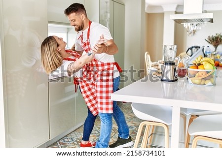 Young couple smiling confident dancing at kitchen