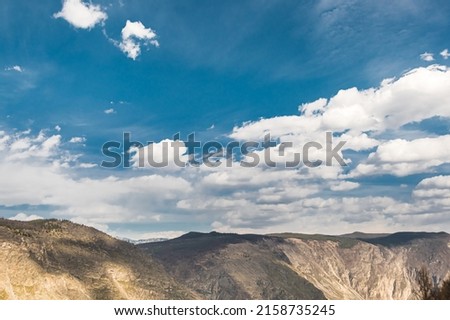 Mountain range under blue sky with cumulus clouds. Rocks and cliffs on horizon on sunny day. Travel through highlands on foot.