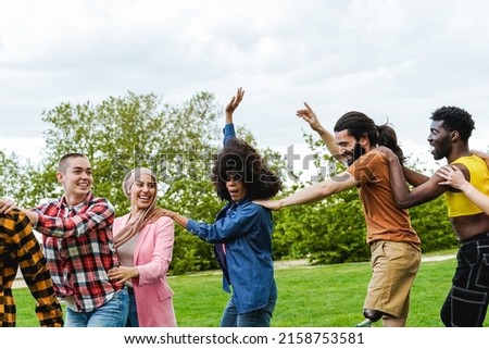 Multiethnic group of diverse friends having fun dancing together outdoor during summer vacations - Focus on man with leg prosthesis