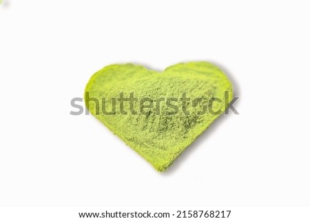 A close-up shot of a heart shaped powdered young barley isolated on white background