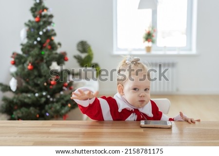 Child girl dressed in christmas dress with cochlear implants having fun at home - diversity and hearing aid and innovating technologies for treatment of deafness. Copy space and place for advertising