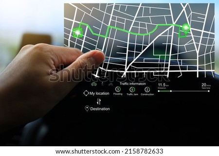 The driver holds the steering wheel to study the route from green virtual GPS on the console of the car for better vision while driving. Do some research before drive set off and navigate on the way.