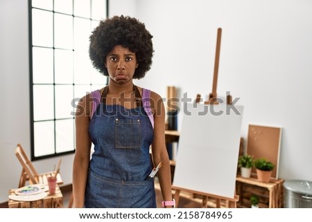 Young african american woman with afro hair at art studio depressed and worry for distress, crying angry and afraid. sad expression. 