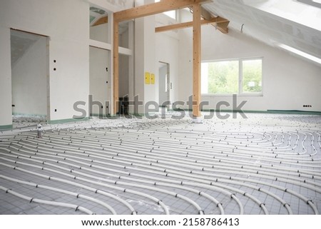 Shot of construction site in a loft where underfloor heating has just been installed, white pipes on grey mat Royalty-Free Stock Photo #2158786413