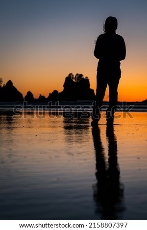 A vertical shot of a silhouette of a person at sunset on Shishi Beach in Washington