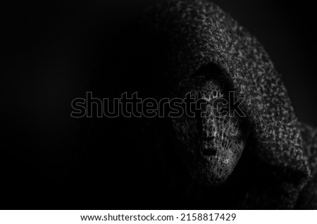 A portrait of a deamon in a dark mask on a black background with copy space