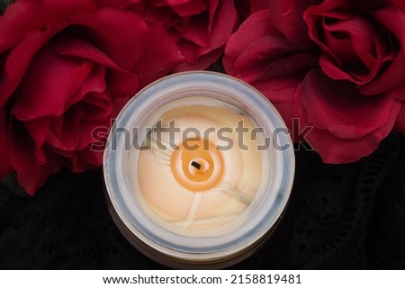A top view of an extinguished candle with romantic red roses