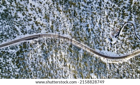 An aerial view of a beautiful winter landscape with a road and trees covered in snow