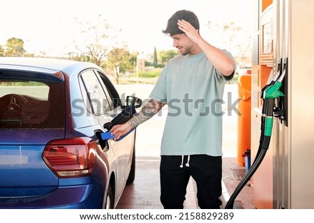 Young man with credit card and hand on head shocked by gas prices