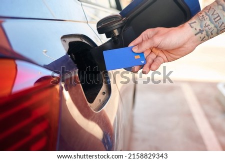 Close-up shot of a man with a credit card near a car gas tank