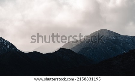 An Aerial shot of snowy dry mountains under a cloudy sky