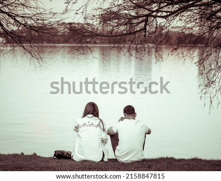 Vintage monochrome photo with a couple sitting on the edge of a lake relaxing