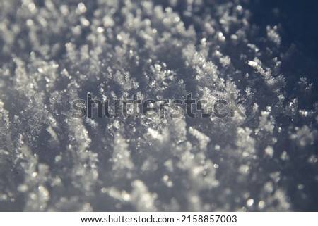 A closeup of tiny white frozen snowflakes in sunlight in winter Royalty-Free Stock Photo #2158857003