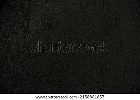 Dark background of decorative plaster with abstract spots. Unusual black or gray wall texture with beautiful patterns, creative surface background. Finishing coating for building cladding.