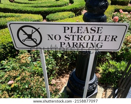The close up view of a rectangular sign that reads "PLEASE NO STROLLER PARKING" with a symbol showing no strollers allowed.