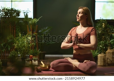 modern middle aged woman at modern green home doing yoga.