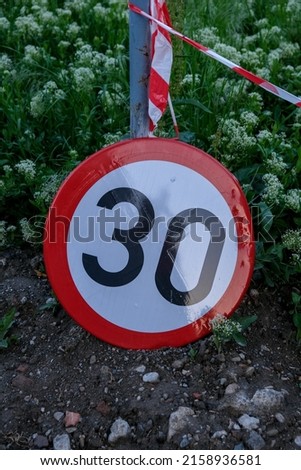 A vertical shot of speed limit sign on the ground, 30kmh