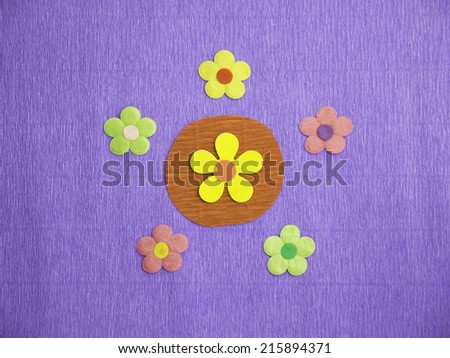 Symmetrical patterns of 5 colorful flowers on a blue crepe-paper background with a big yellow flower at its center