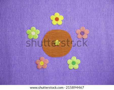 Symmetrical patterns of 5 colorful flowers on a blue crepe-paper background with a tiny yellow flower icon at its center