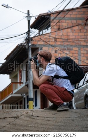 Young White Man Wearing a Brown Cap Takes a Photo of the Town
