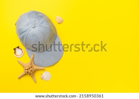 Blue cap and seashells on color background, top view.