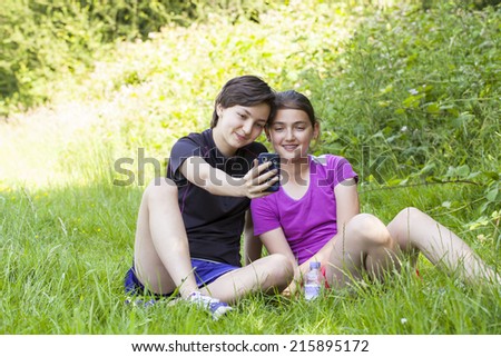 Two teenage girls taking photos of themselves with the phone