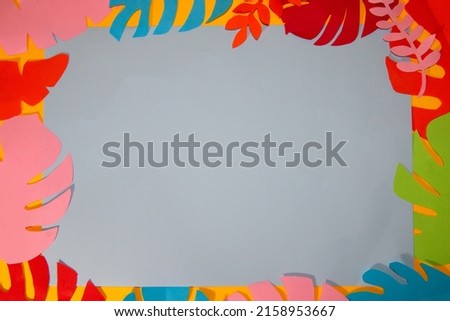 gray background for copy space surrounded by colorful jungle leaves, creative summer tropical design, flat lay