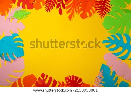 yellow background for copy space surrounded by colorful jungle leaves, creative summer tropical design, flat lay