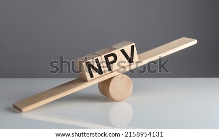 NPV on wooden cubes on wooden balance , business concept