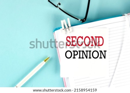 SECOND OPINION text on sticky on notebook with pen and glasses , blue background Royalty-Free Stock Photo #2158954159
