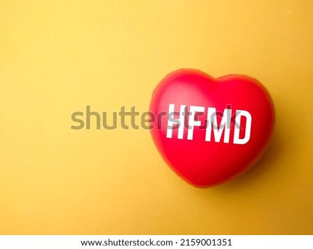 Top view red heart with the word HFMD on a yellow background. Medical and health care concept