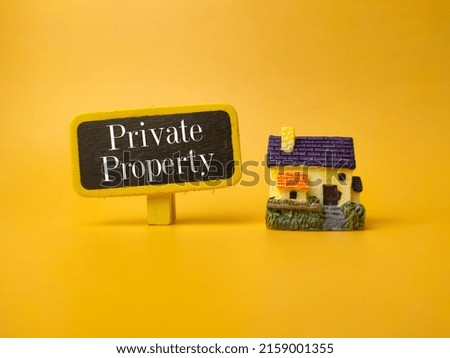 miniature house and wooden board with the word Private Property on yellow background 