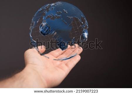 A floating globe over a hand against a dark background-global network concept