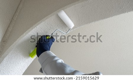 A worker who paints the outer wall with a paint roller. Royalty-Free Stock Photo #2159015629